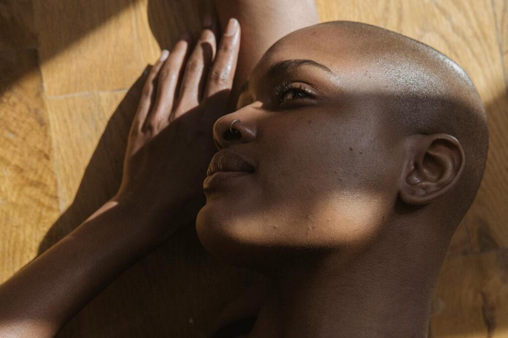 From above side view of African American female with shaved head looking up while lying on floor