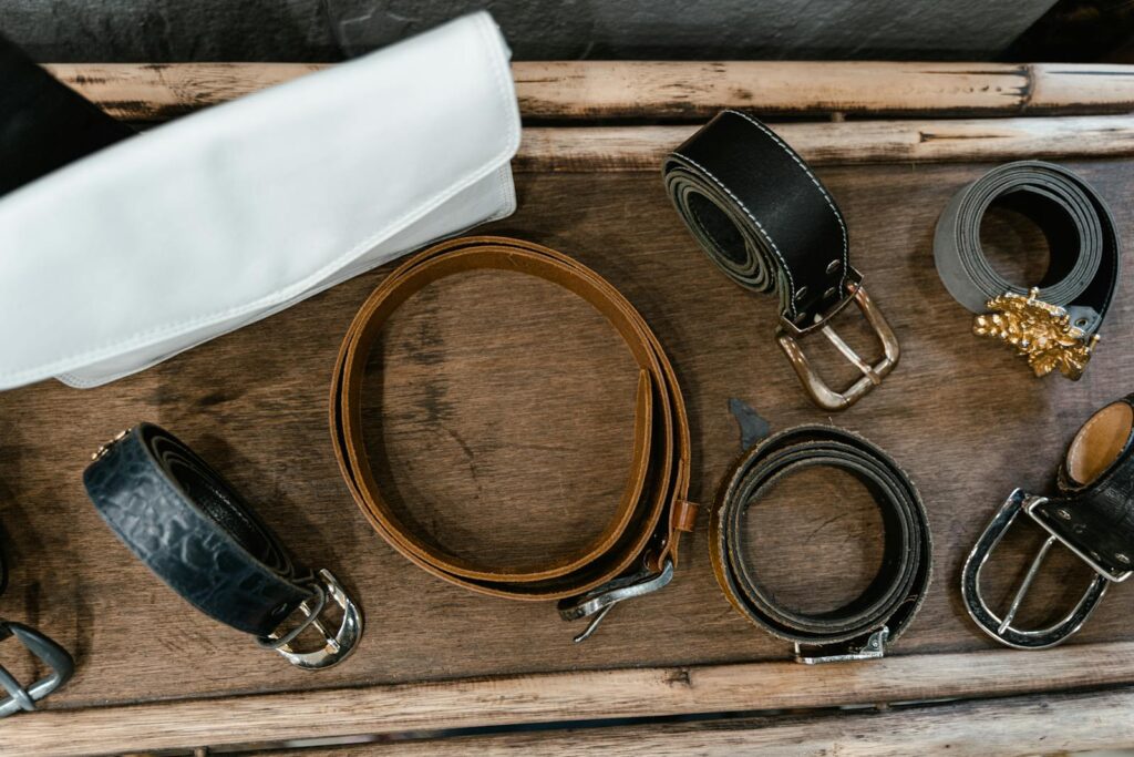 Top view of rolled leather belts arranged on a rustic wooden surface.