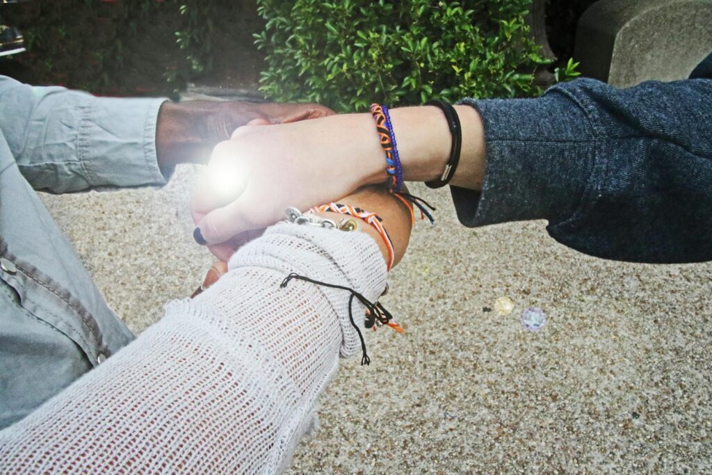 Three people showcasing unity with hands joined and bracelets in an outdoor setting.