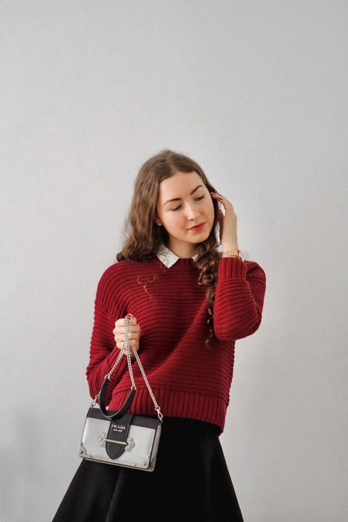 woman in red sweater holding her hair