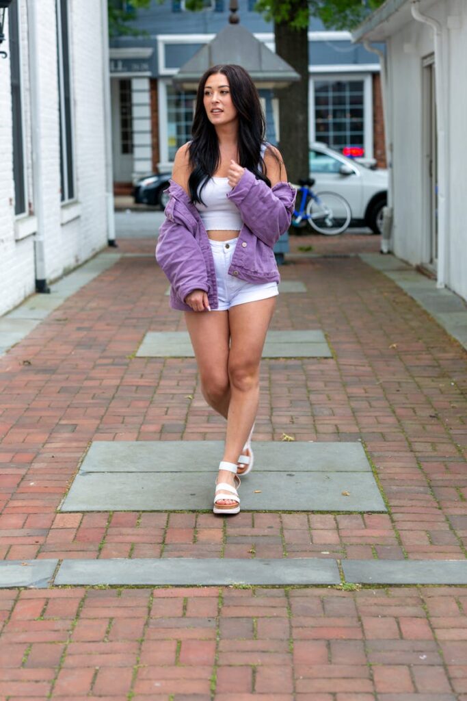 Fashionable woman walks on urban street in denim and crop top.