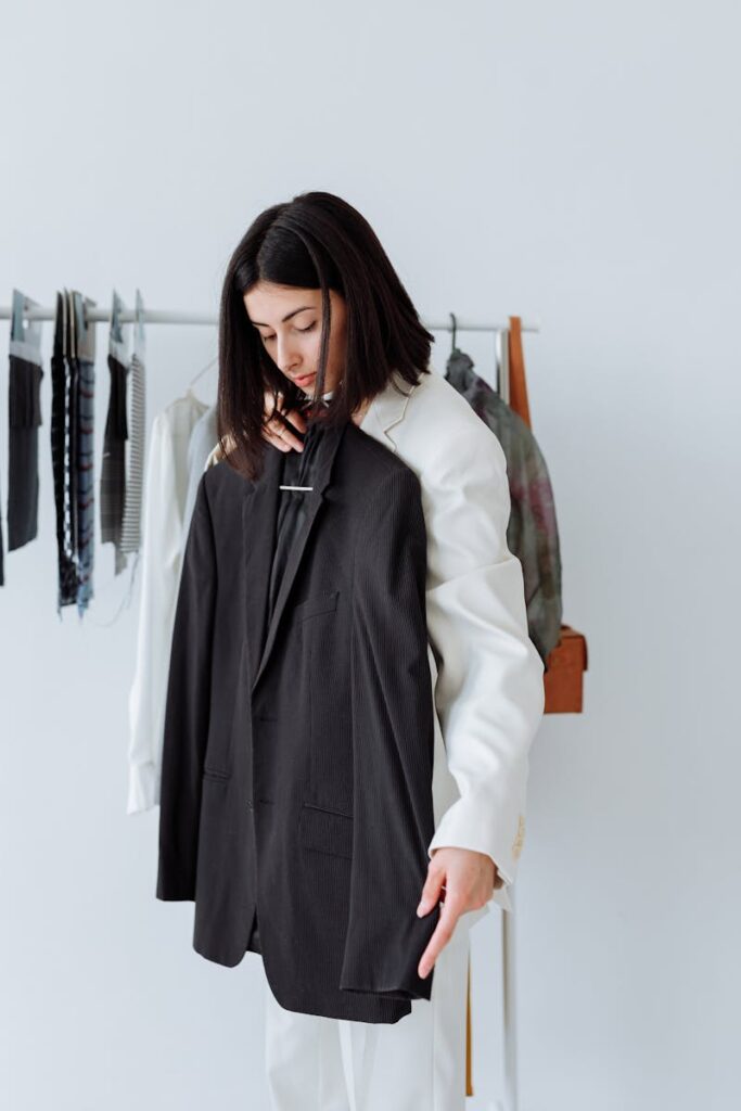 Woman selecting a black blazer in a modern fashion store setting.