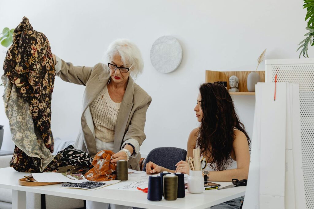 Two women in a fashion studio discussing fabrics and designs for a project.