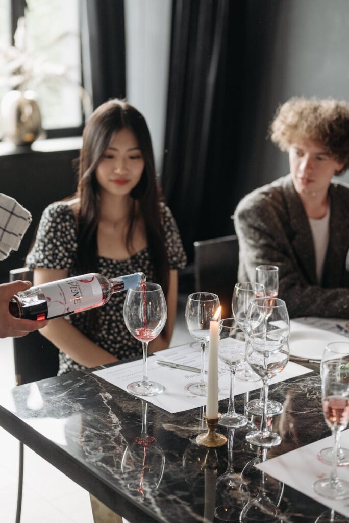 Elegant dining scene with wine pouring, candles, and a diverse group of adults.