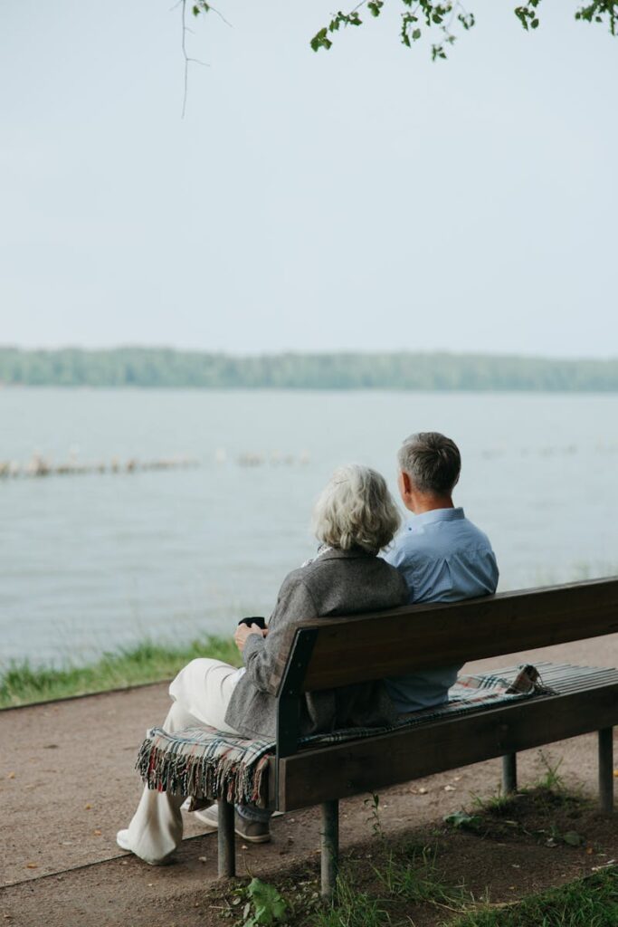 Senior couple sitting on a bench, enjoying a peaceful view by the lake.
