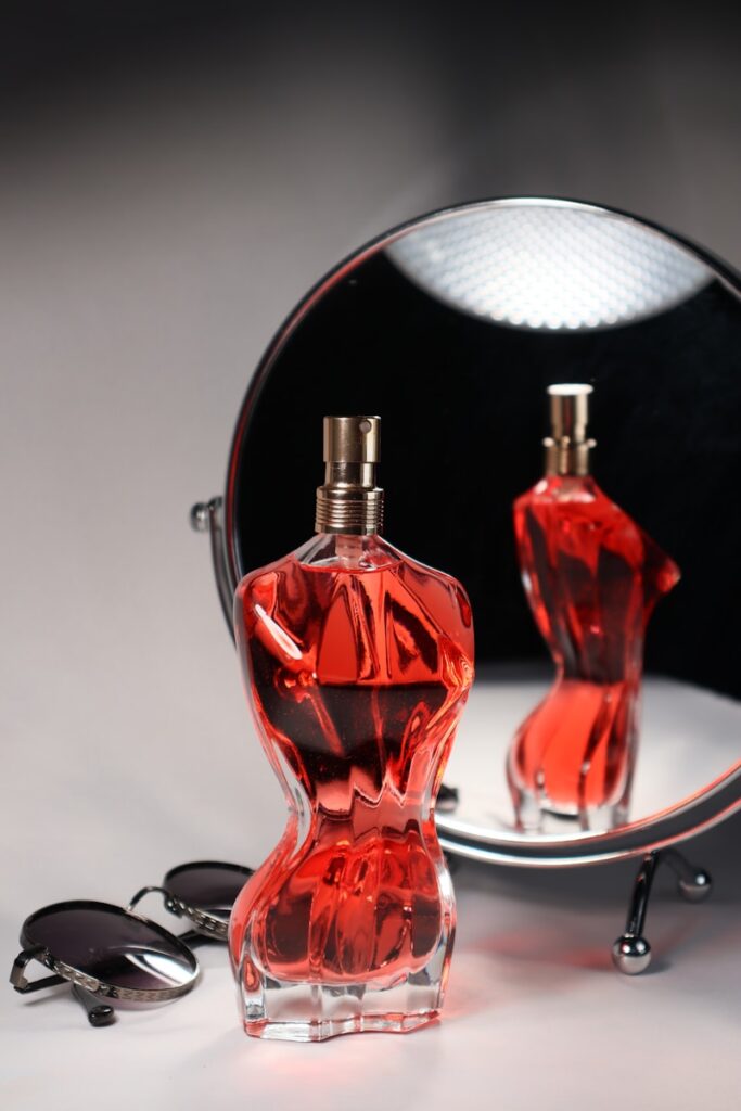 A perfume bottle is reflected in a mirror.