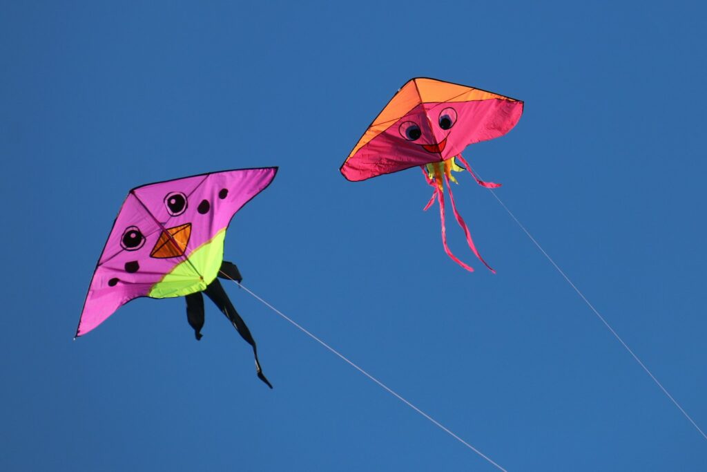 low angle photography of two pink and orange kites