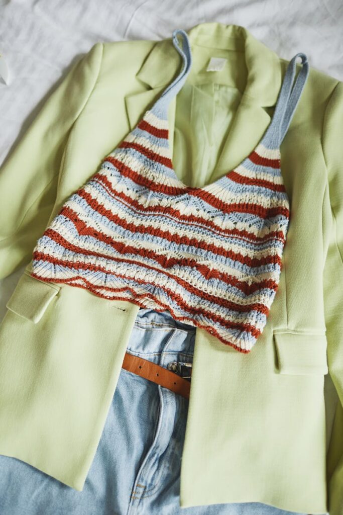 Fashionable knit crop top with striped pattern on a lime green blazer and denim jeans.