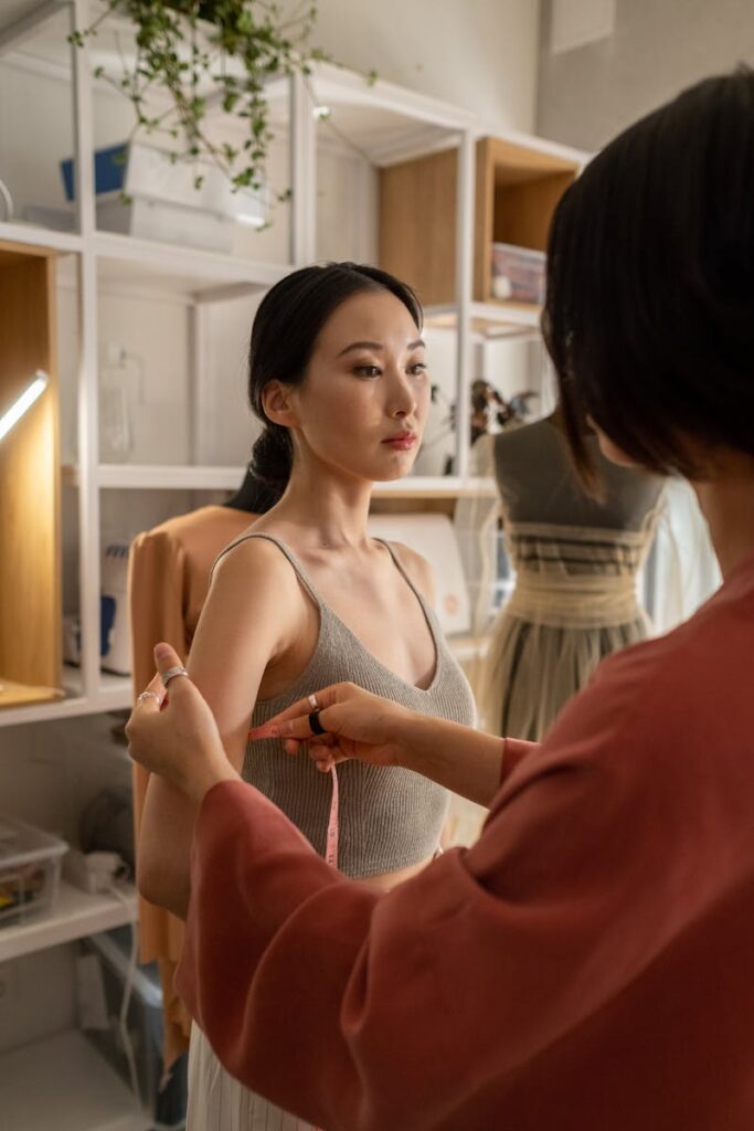 Fashion designer taking measurements of a model in a stylish studio setting.