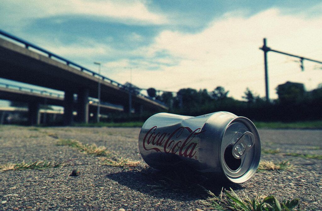 A discarded Coca-Cola can lies near an overpass, showcasing urban littering.
