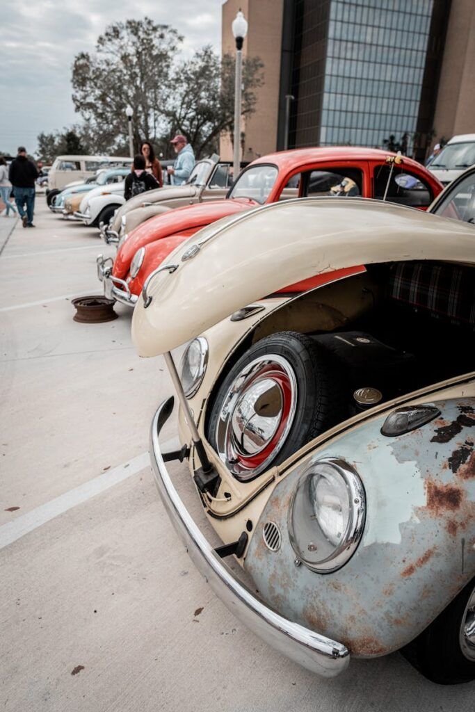 A lineup of vintage Volkswagen Beetles displayed at an outdoor car show, showcasing classic design.
