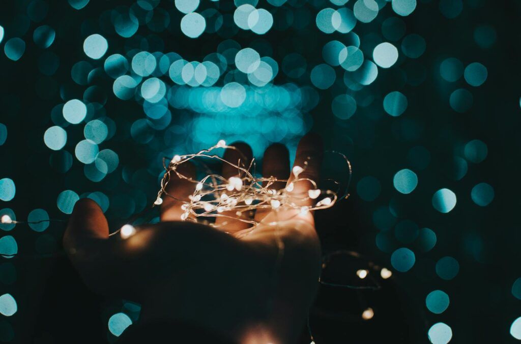 A mesmerizing shot of string lights glowing softly in a hand against a bokeh background.