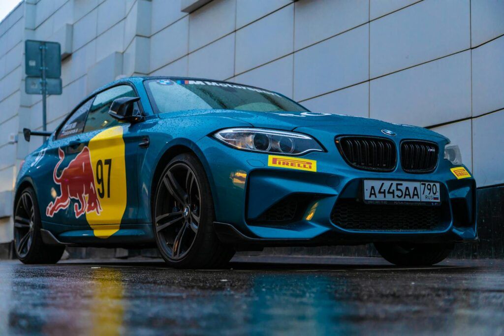 A sleek BMW sports car featuring vibrant decals parked on rainy streets of Moscow.