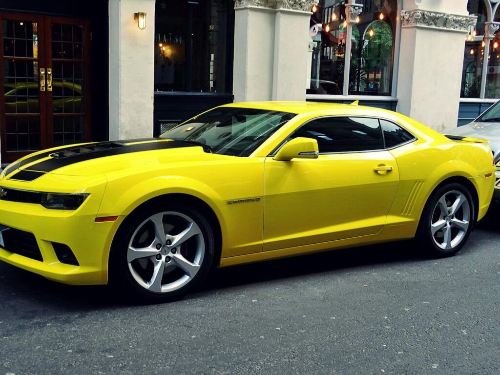 A stylish yellow Chevrolet Camaro parked on a city street, showcasing its sporty design.