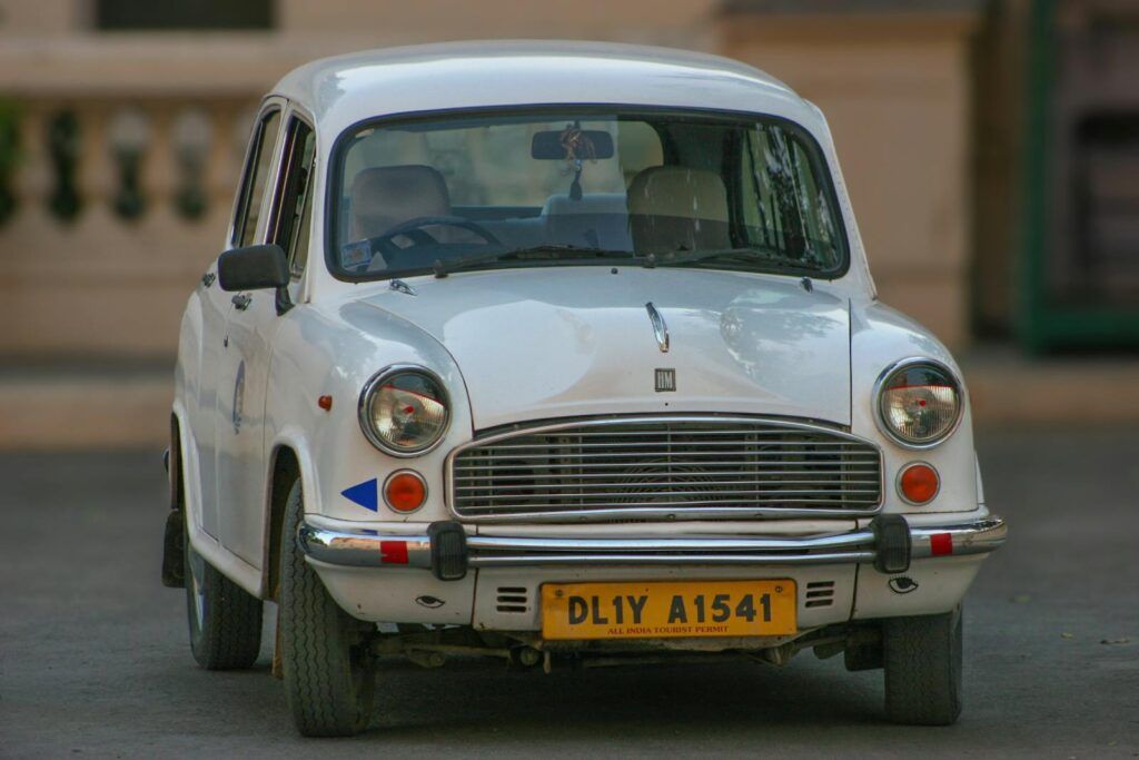A vintage Hindustan Ambassador car with a Delhi license plate parked outdoors.
