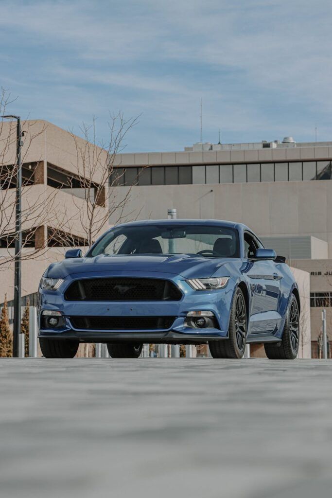 Blue Ford Mustang parked in a modern urban environment, showcasing sleek design and power.