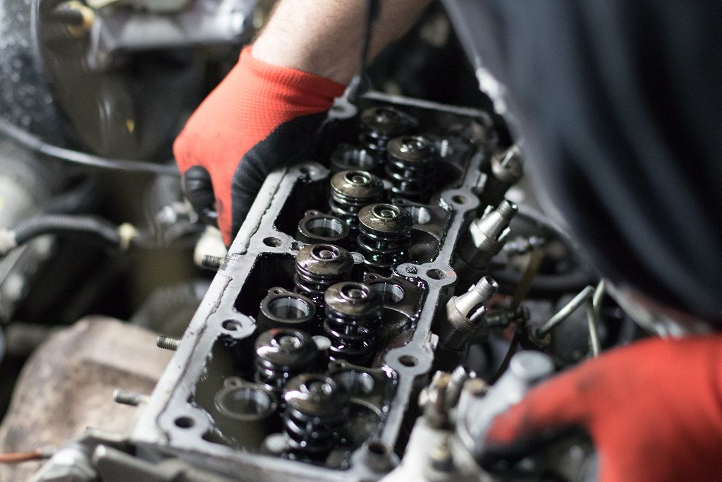 Car mechanic removing the cylinder head from a car engine