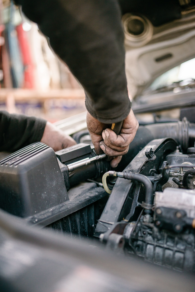Car mechanic working on an old engine under hood