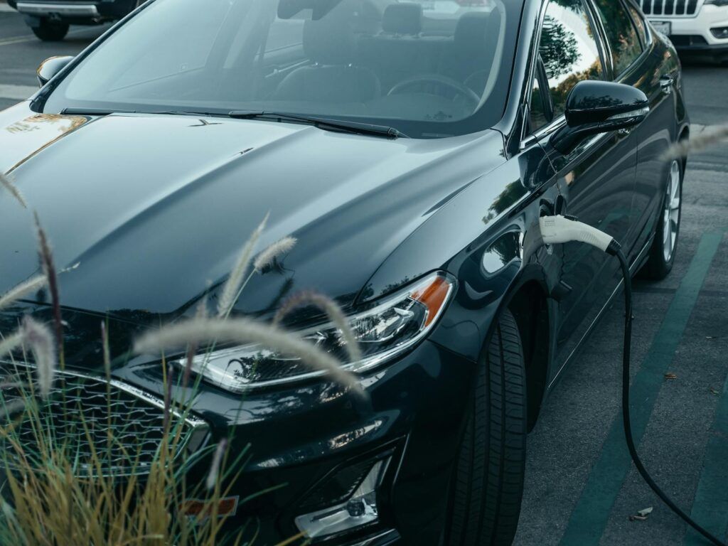 Close-up of an electric car charging at a station in a city parking lot, showcasing clean energy technology.
