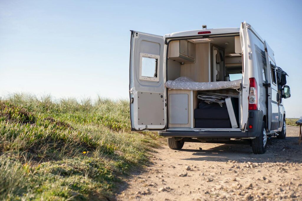 Open camper van on a sunny day, perfect for a rural getaway in nature.
