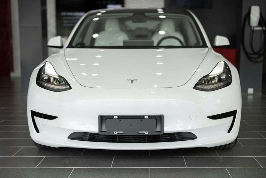 Sleek white electric car on display in a modern dealership showroom.