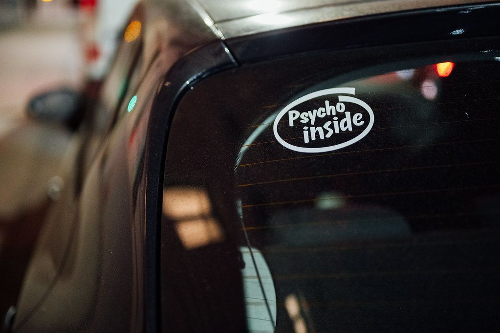 Sticker on a car's rear windshield with text 'Psycho inside'