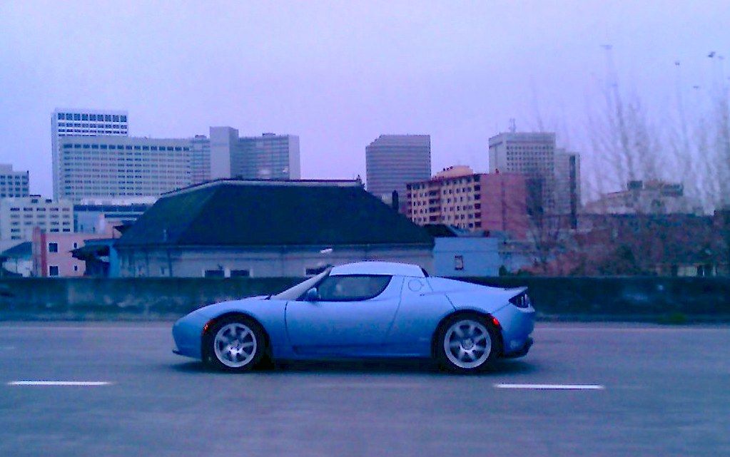 Tesla plug-in electric car, left side profile, on freeway