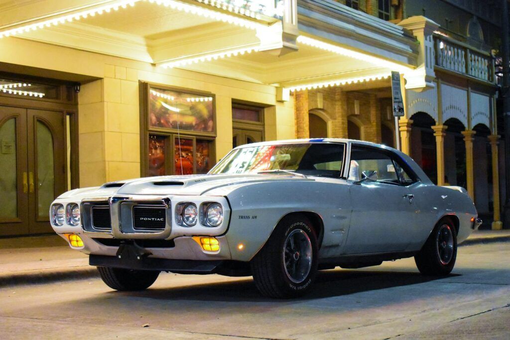 Vintage Pontiac Firebird Trans Am parked on a lit street at night.