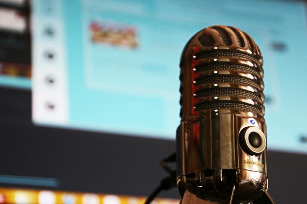 Vintage microphone in focus against a blurred computer screen background.
