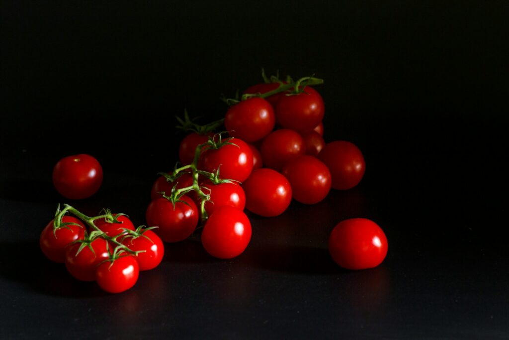 Red cherry tomatoes sit against a dark backdrop.