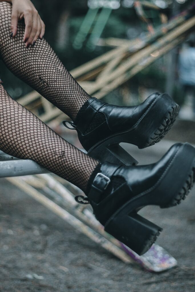 woman in black leather boots sitting on brown wooden bench