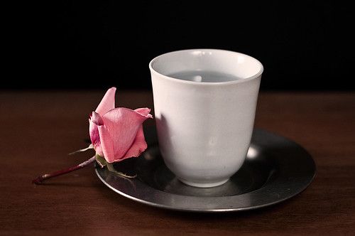 cup of water and a rose on a silver plate.