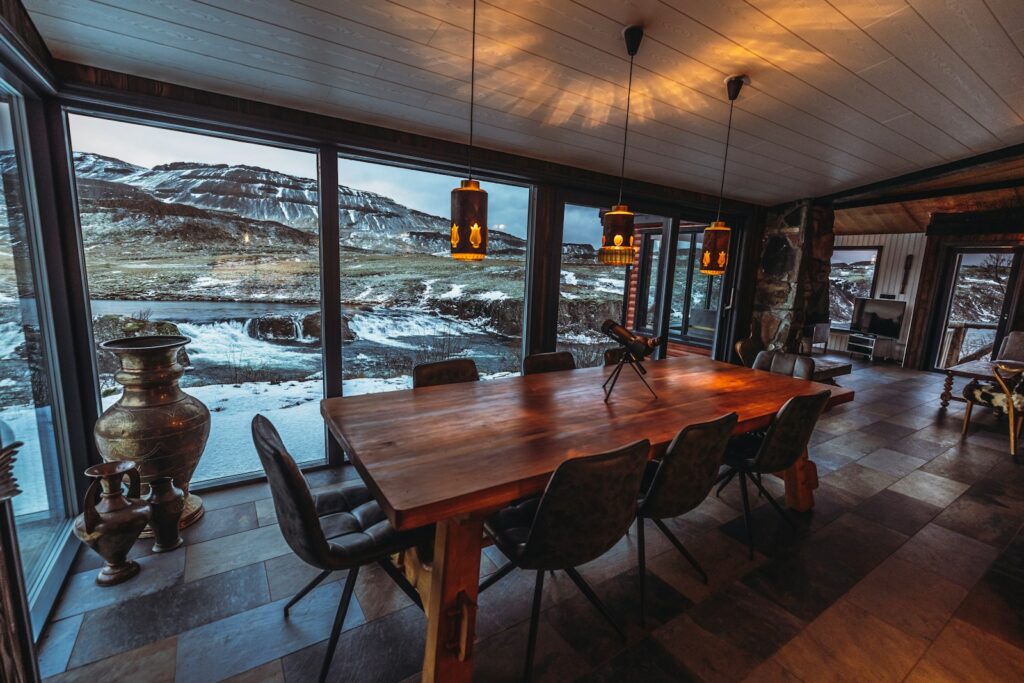 a dining room with a large wooden table surrounded by windows