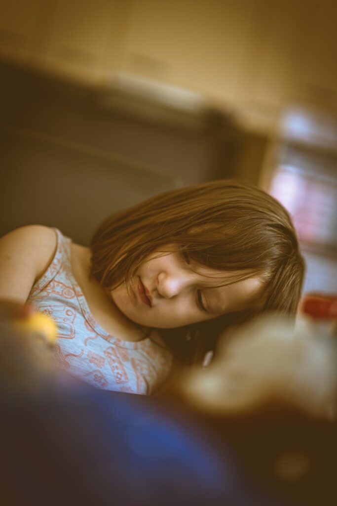 A young girl laying in bed with her eyes closed