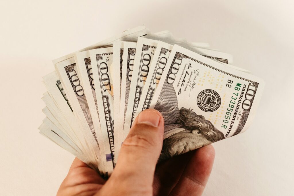 a hand holding a bundle of twenty dollar bills