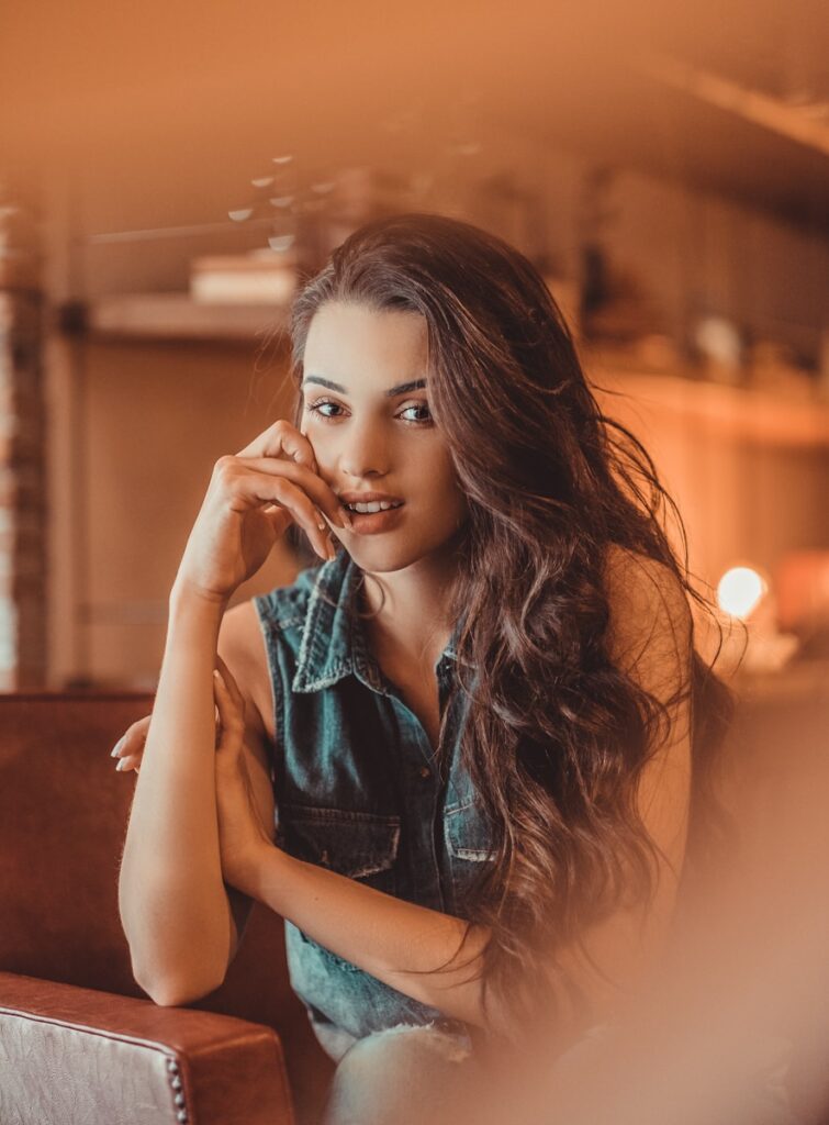 a beautiful young woman sitting on top of a brown chair