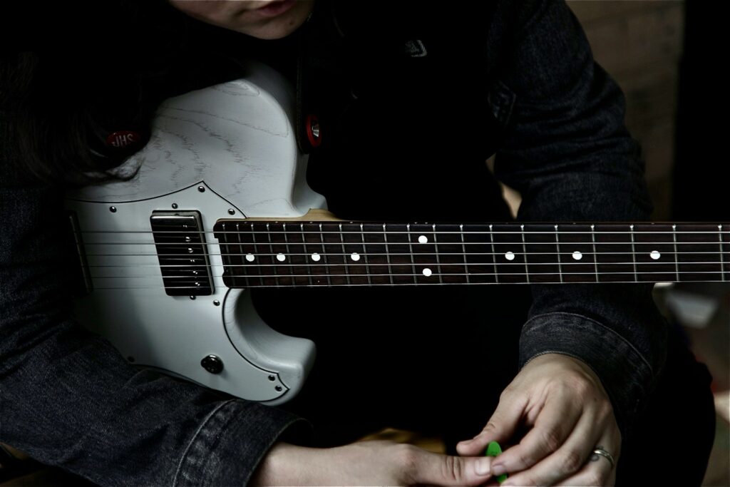 man in black long sleeve shirt playing white electric guitar