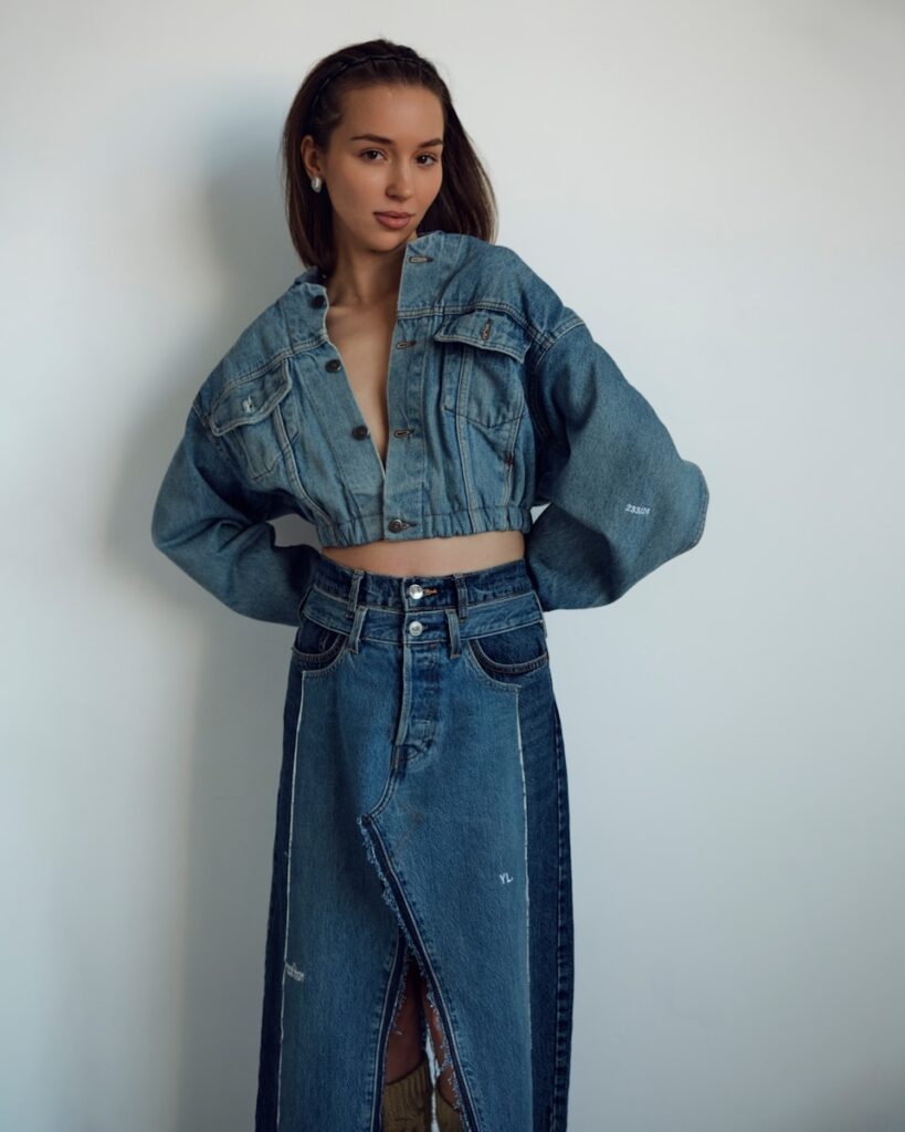 A woman models a stylish denim jacket and skirt.