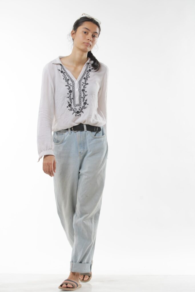 a woman standing in a white shirt and jeans