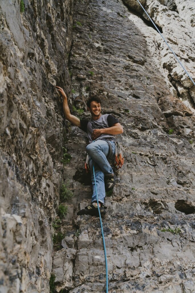 woman in gray t-shirt climbing on rocky mountain during daytime