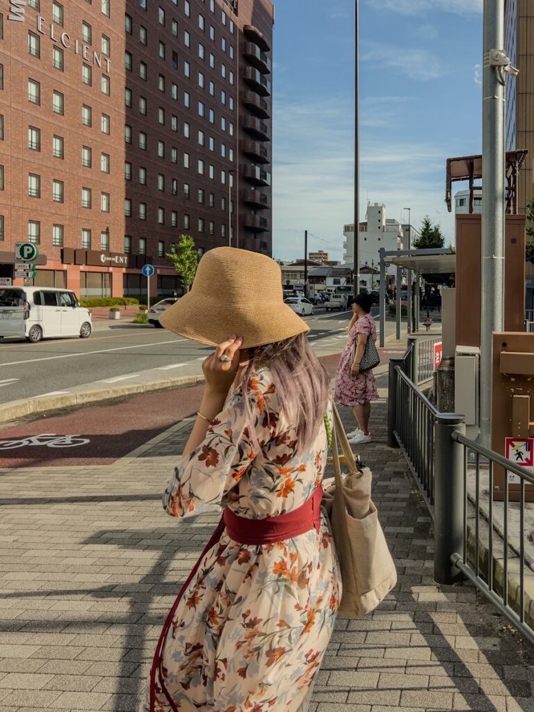 A woman in a dress and hat walking down a sidewalk