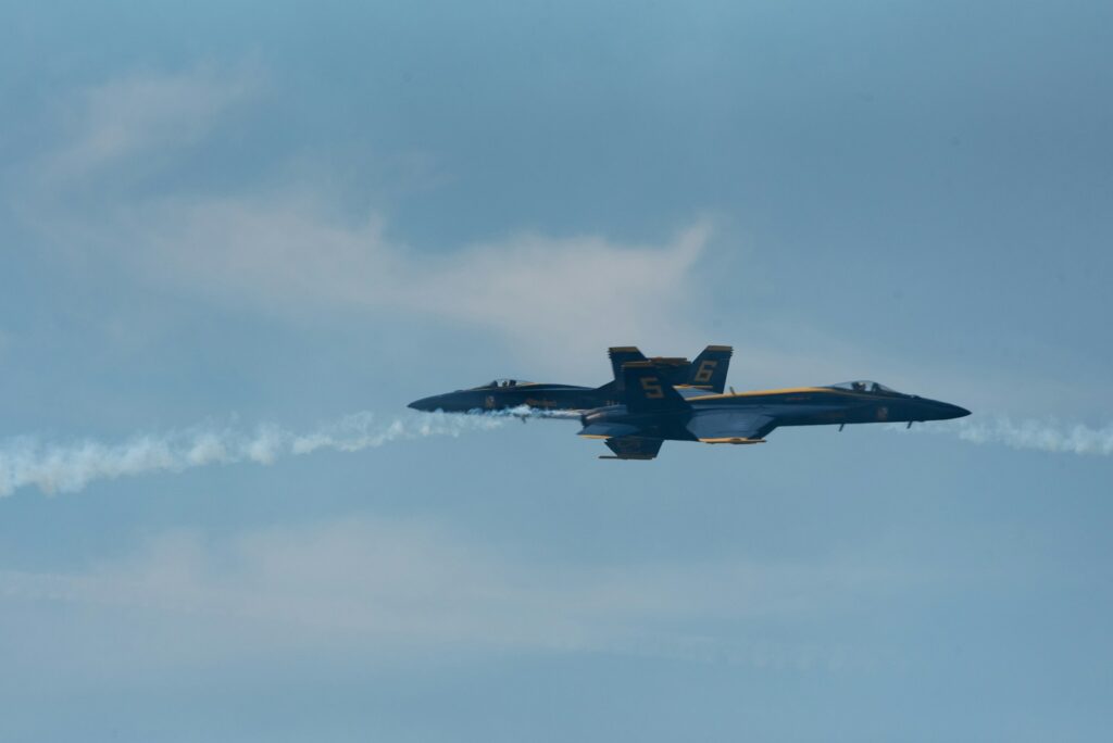 a fighter jet flying through a cloudy blue sky