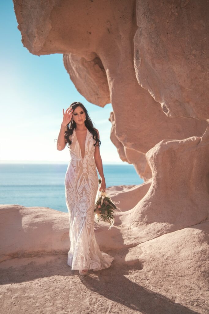 a woman in a wedding dress walking on the beach