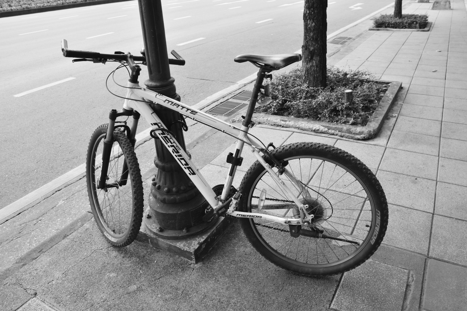 a bicycle is chained to a pole on the sidewalk