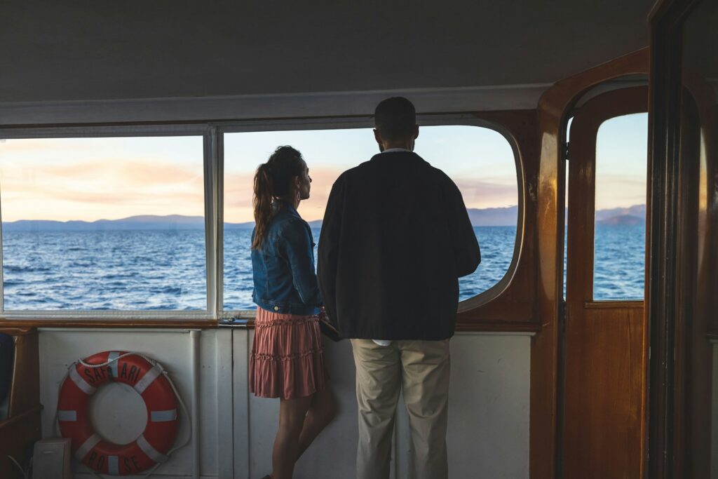 a man and a woman standing on a boat looking out the window