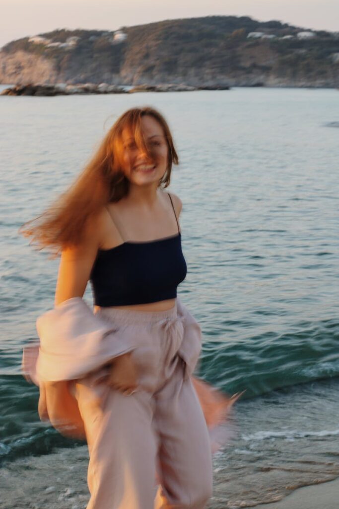 Smiling woman enjoying a beachside sunset, embracing the moment.