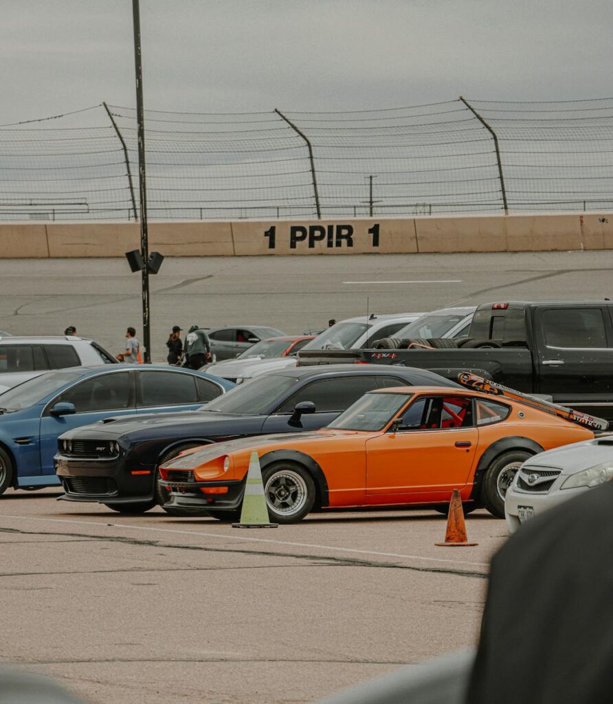 A vintage Datsun S30 parked among modern cars at a racing event.