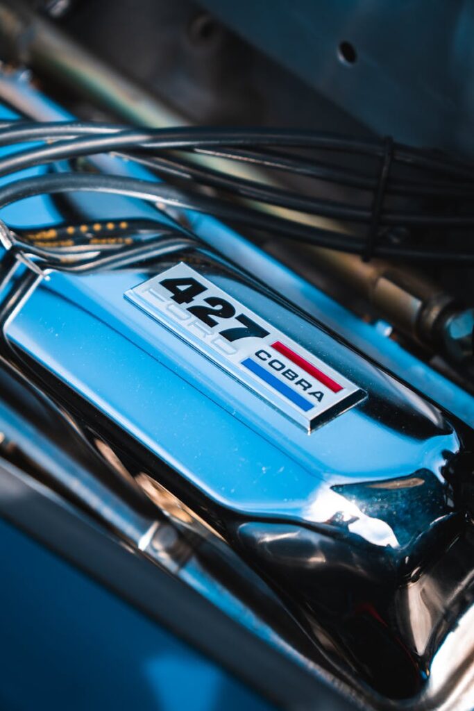 Detailed shot of a Ford Shelby Cobra engine with a 427 chrome cover, showcasing automotive beauty.