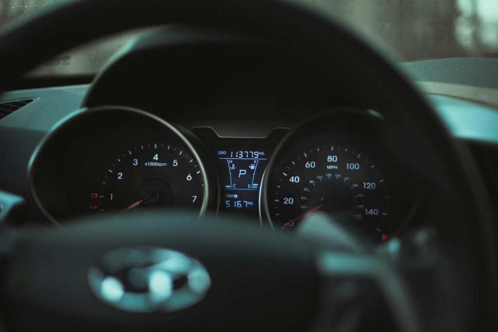 Focus on a car dashboard showing odometer and rev counter in dim light.
