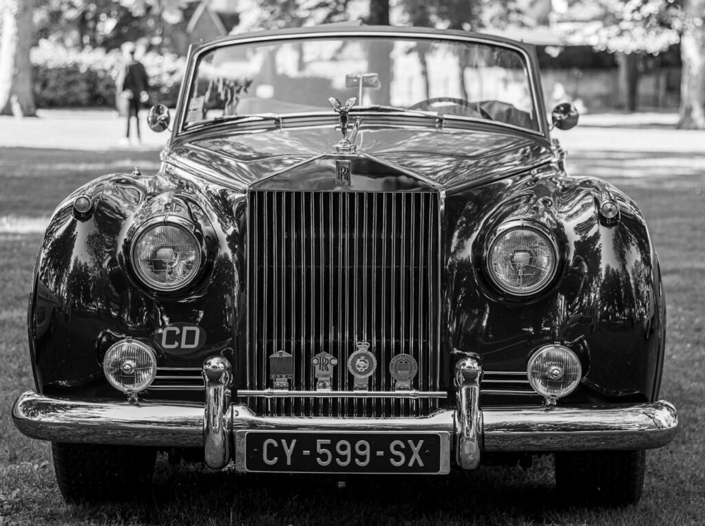 Front view of a vintage Rolls-Royce Phantom V in a monochrome outdoor setting.